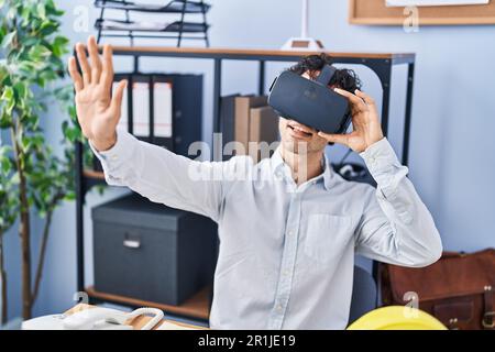 Young hispanic man architect smiling confident using virtual reality glasses at office Stock Photo