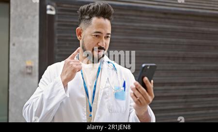 Young latin man doctor having video call at street Stock Photo