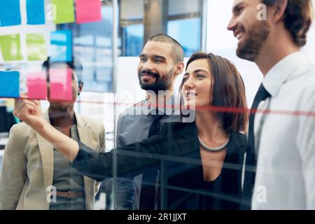 Teamwork, collaboration of diverse coworkers with sticky notes on wall and working in office. Startup or project, support or communication and team Stock Photo