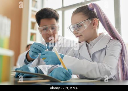 Side view portrait of two children enjoying experiments during science class in school Stock Photo