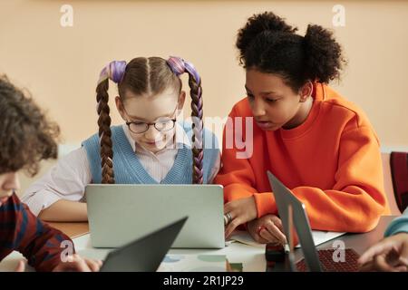 Portrait of two teen schoolgirls using laptop together in class and studying together Stock Photo