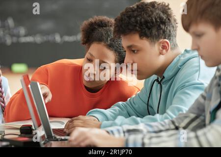 Children using laptop in school classroom focus on black girl looking at computer screen Stock Photo