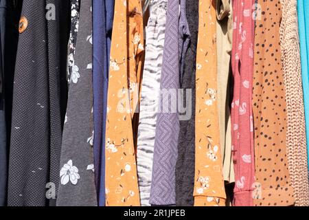Background of cheap colorful summer dresses hanging back to back in the sun at an open-air market in the Netherlands Stock Photo