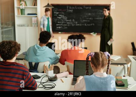 Back view at diverse group of children using computers at desks in school classroom Stock Photo