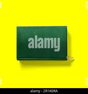 Back to school concept , hard cover dark green book front close isolated on yellow. Stock Photo