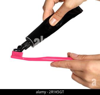 Woman applying charcoal toothpaste on brush against white background, closeup Stock Photo