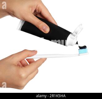 Woman applying charcoal toothpaste on brush against white background, closeup Stock Photo