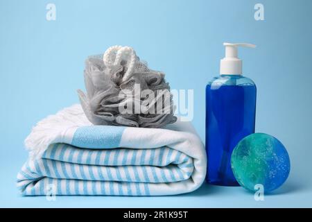 Grey shower puff, cosmetic products and towel on light blue background Stock Photo