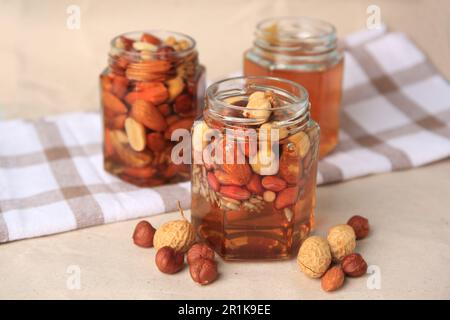 Jars with different nuts and honey on beige table Stock Photo