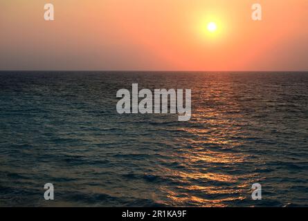 Sea waves and the setting sun on the horizon. Yellow sun rays reflected in the seawater Stock Photo