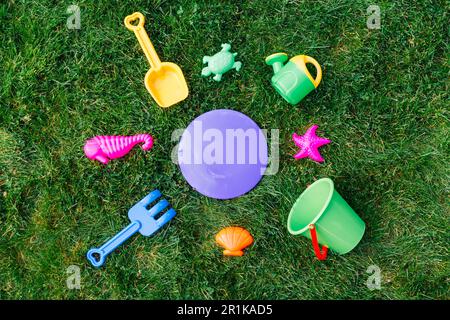 close up of sand toys kit on green lawn or grass Stock Photo