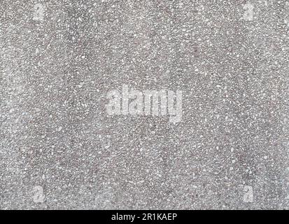Front view of a concrete wall with small stones on the surface. Abstract high resolution full frame textured background. Stock Photo