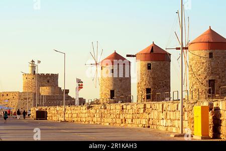Three stone medieval windmills with red roofs.The fortress wall around the lighthouse of St.Nicholas.Flags of different countries along the embankment Stock Photo