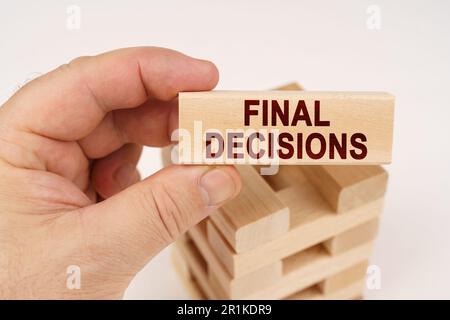 Business concept. A man holds in his hands a wooden block with the inscription - Final Decisions Stock Photo