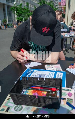 The Hague, Netherlands. 13th May, 2023. A male Russian ex-pats with baseball cap, is seen writing a postcard of solidarity, to be shared with a political prisoner jailed in Putin's Russia. The last day of the #FreeNavalny cell exhibition in The Hague. Aleksei Navalny is a Russian opposition and anti-corruption activist, who was detained and has been imprisoned for now 11 years and 6 months. (Photo by Charles M Vella/SOPA Images/Sipa USA) Credit: Sipa USA/Alamy Live News Stock Photo