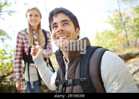 Helping her climb down safely. A handsome young hiker helping his girlfriend as they hike down a mountainside. Stock Photo