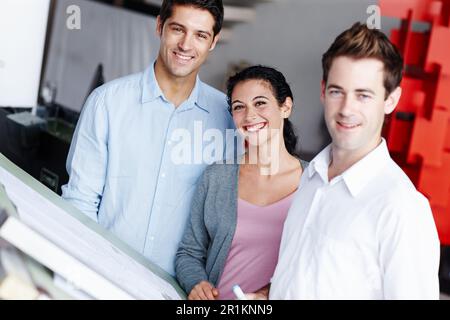 Team of successful architects. Portrait of three talented architects working on their design blueprints together. Stock Photo