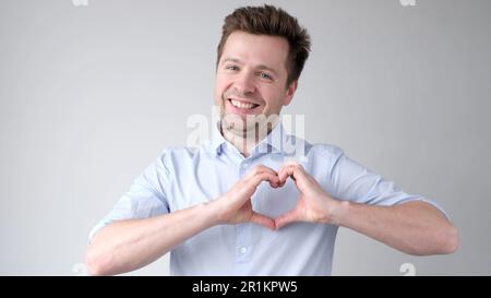 European young man shows a heart sign and confesses love Stock Photo