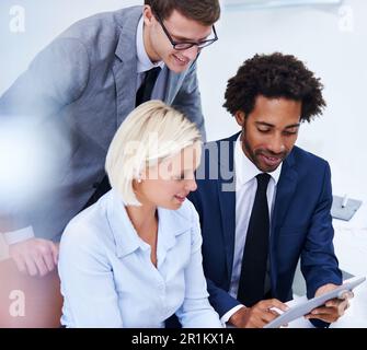 Sharing the latest digital updates. a group of businesspeople looking at a digital tablet. Stock Photo
