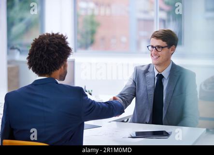 Starting the meting with confidence. two businessmen shaking hands over a desk. Stock Photo