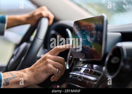 Man traveler sitting in car using gps navigation on monitor while driving. Stock Photo