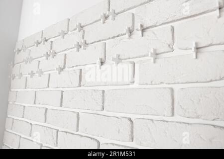 Decorative white bricks with tile leveling system on wall Stock Photo
