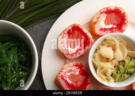 Delicious sushi rolls with wasabi, ginger and chuka on grey textured table, flat lay Stock Photo