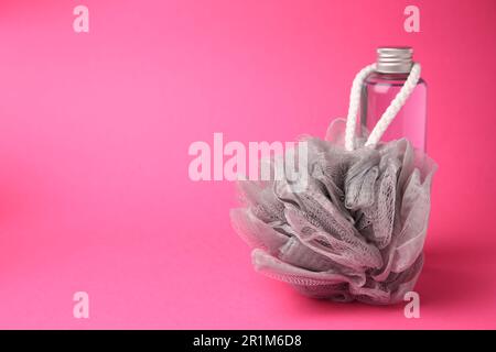 Grey shower puff and bottle of cosmetic product on pink background, space for text Stock Photo