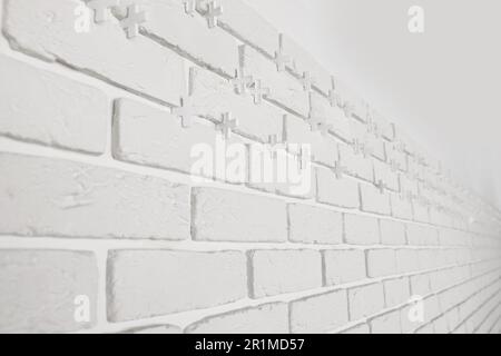 Decorative white bricks with tile leveling system on wall Stock Photo