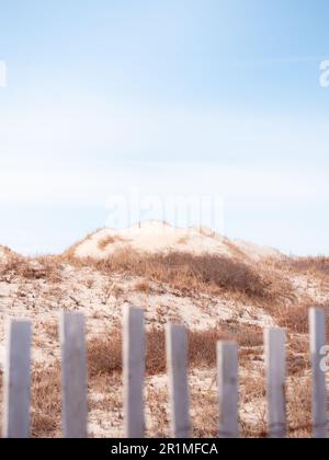 A view of hilly sand dunes covered in dune grass next to the ocean. These sand dunes are at Horseneck Beach in Westport Massachusetts. Stock Photo