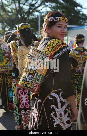 An Orang Ulu girl dressed in her beautiful beaded outfit with a baby carrier in Kuching, Sarawak, Malaysia, Borneo. Stock Photo