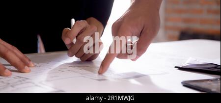 Closeup hands young caucasian architect woman looking laptop and working drawing blueprint for planning building house, engineer thinking and sketchin Stock Photo