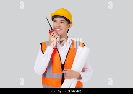 Portrait young asian engineer man wearing helmet using radio for speak command with worker isolated white background, handsome male is architect or co Stock Photo