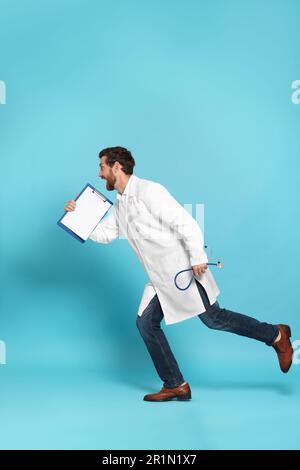 Doctor with stethoscope and clipboard running on light blue background Stock Photo