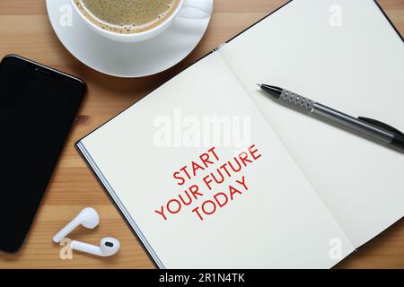 Phrase Start Your Future Today in notebook, smartphone, coffee and stationery on wooden table, flat lay Stock Photo