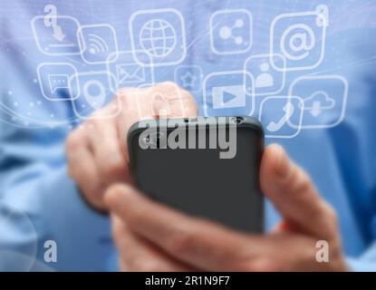 Man in blue shirt holds mobile phone. Symbols and icons of mobile internet, social networks, emails, cloud storage, multimedia services and so on. Mob Stock Photo