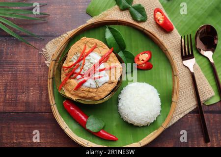 Steamed fish curry in banana leaf cups served with white rice - Famous Thai food called Hor Mok or fish Amok at top view on wooden background Stock Photo