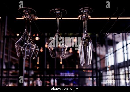 Lots of empty wine glasses hanging on the bar in a cafe or restaurant. Dark interior Stock Photo