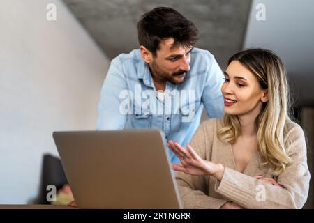 Multiethnic colleagues discussing project while working with laptop in office indoors Stock Photo