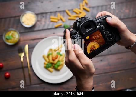 High angle view of photographer making photo of food on table on his professional camera Stock Photo