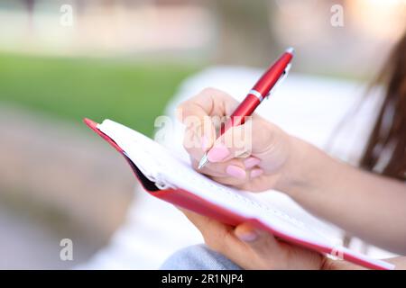 Close up of a hand wrting in paper agenda in the street Stock Photo