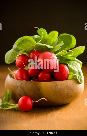 A bunch of fresh radishes  in wooden bowl Stock Photo