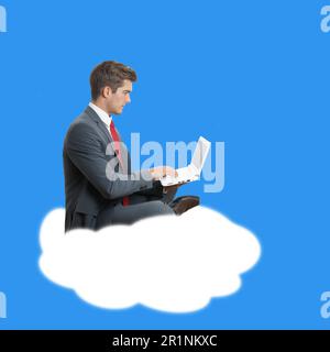 Young businessman with laptop sitting on a cloud symbolising cloud computing Stock Photo