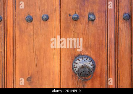 Vintage metal handle on old brown wooden door with metal rivets very close front view Stock Photo