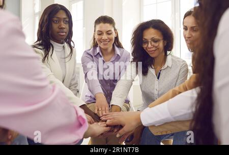 Diverse smiling business people women putting their arms together in a stack. Stock Photo