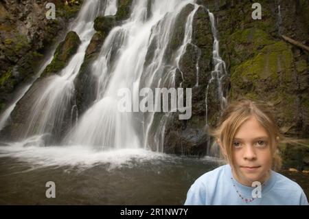A young girl stands in front of Passage Creek falls on the passage Creek trail. Stock Photo