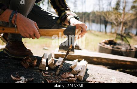 Man using an Axe to chop wood for a camp fire in the forest Stock Photo