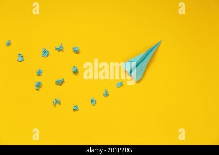 Handmade plane and many crumpled pieces of paper on yellow background, flat lay Stock Photo