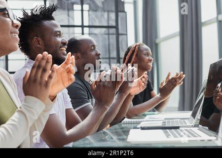 Multi ethnic business group greets somebody with clapping and smiling Stock Photo