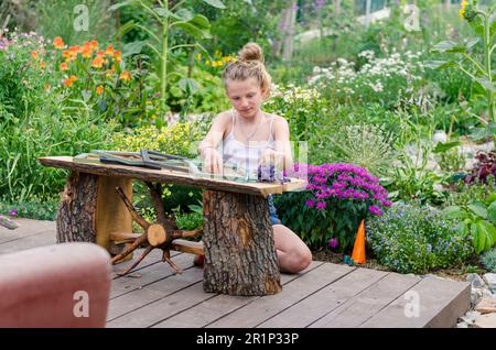 blond child in green garden holding lavender flowers for creative ideas into wooden frames Stock Photo